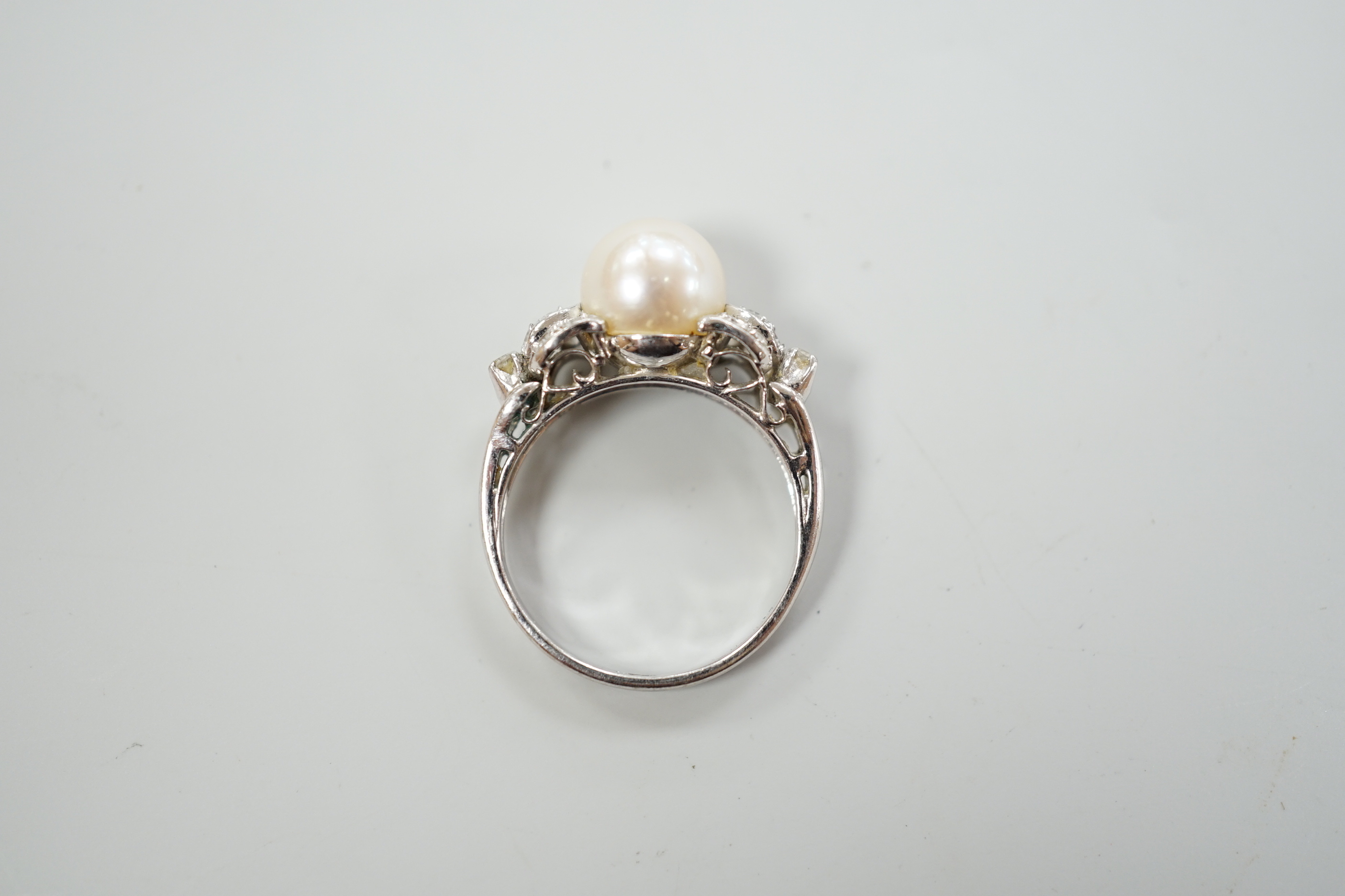 A 14k white metal and single stone cultured pearl set dress ring, with diamond cluster set shoulders, size J, gross weight 3.4 grams.